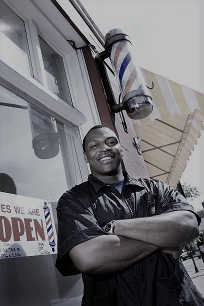 barber standing proudly outside barbershop